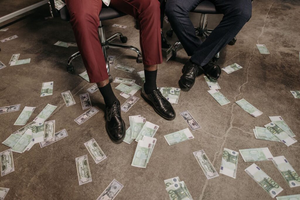 Two people in an office with euro banknotes scattered on the floor, showcasing a financial theme.